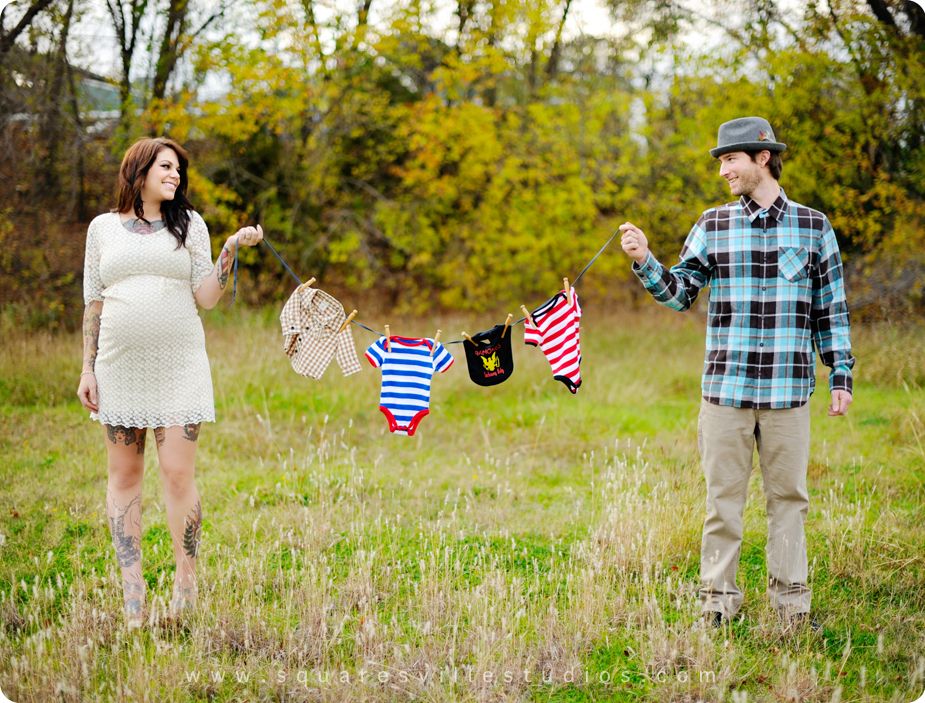 Couples maternity photos with hanging baby clothes props